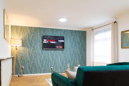 a living room with a couch and a tv on a wall at DELUXE Tranquil Central 2 Bedroom Home-Free Parking, WIFI, Garden Views, University of Birmingham, Botanical Gardens, Edgbaston cricket in Birmingham