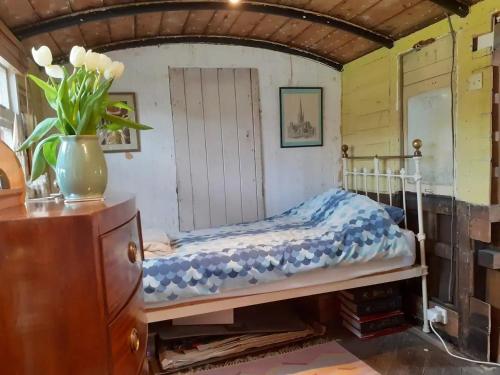 a bedroom with a bed and a vase of flowers at Sundial Cottage in Norwich