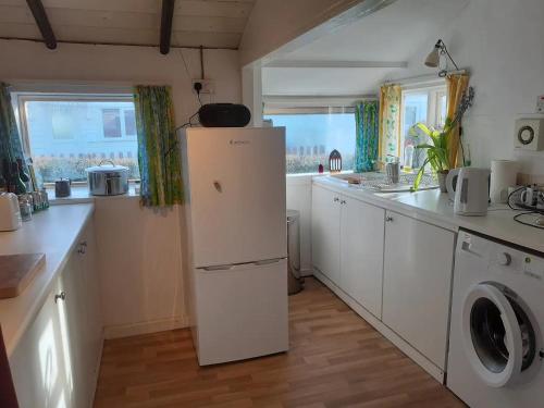 a kitchen with a white refrigerator and a sink at Sundial Cottage in Norwich