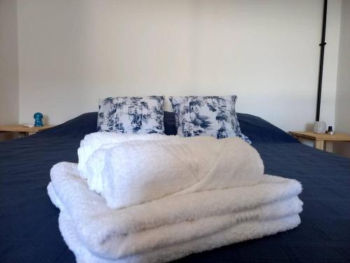 una pila de toallas blancas en una cama con almohadas en TEKOHA, Alquiler Temporario en Posadas! en Posadas