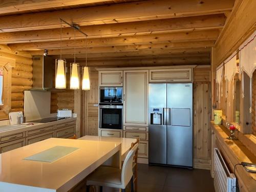 Il comprend une cuisine avec un réfrigérateur en acier inoxydable et des murs en bois. dans l'établissement Saint Bernard, à Font-Romeu-Odeillo-Via