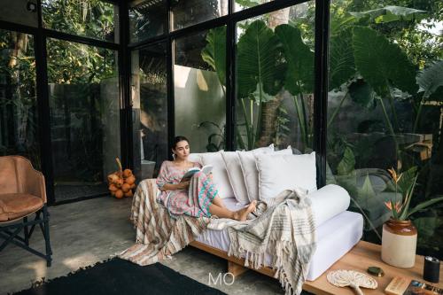 a woman sitting on a couch in a room with windows at Tao House Jungle Boutique Villas in Ahangama