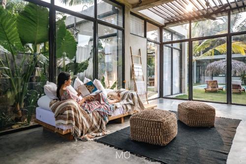 a woman sitting on a couch reading a book in a conservatory at Tao House Jungle Boutique Villas in Ahangama