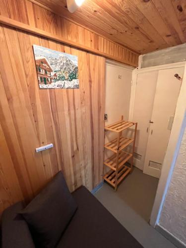 Cette petite chambre est dotée d'un mur en bois et d'une étagère. dans l'établissement Appartement rdc calme6 pers, à Eaux-Bonnes