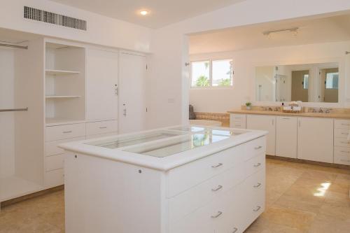 Una cocina blanca con gabinetes blancos y un fregadero. en Stunning 6bd Villa in Palmilla! Fully Staffed w Chauffeur and Yacht included!, en San José del Cabo