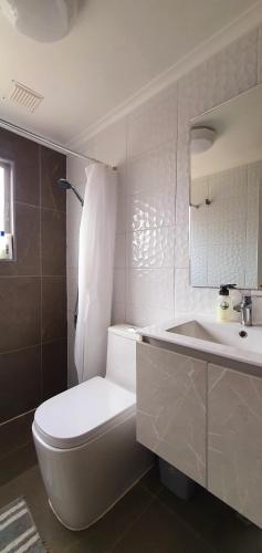 a white bathroom with a toilet and a sink at Casa Descanso Serena in La Serena