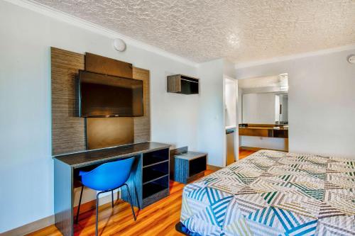 a bedroom with a bed and a desk with a television at Motel 6-Fort Worth, TX - White Settlement in Fort Worth