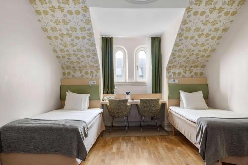 duas camas num quarto com mesa e cadeiras em Best Western Hotel Royal em Malmo