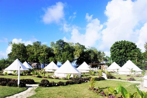 a group of white tents on a grass field at Le Life Resort in Epule