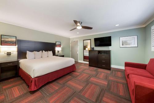um quarto de hotel com uma cama e um sofá vermelho em BEST WESTERN the Inn of Los Gatos em Los Gatos