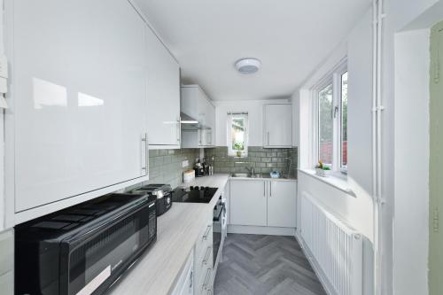 a kitchen with white cabinets and a black microwave at Newark Central Cottage in Newark upon Trent