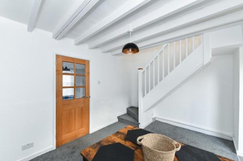 a hallway with white walls and stairs with a wooden door at Newark Central Cottage in Newark upon Trent