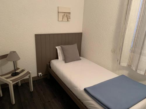 a small bedroom with a bed and a lamp on a table at LOGIS HOTELS - Hôtel et Restaurant L'Océana in Lanton