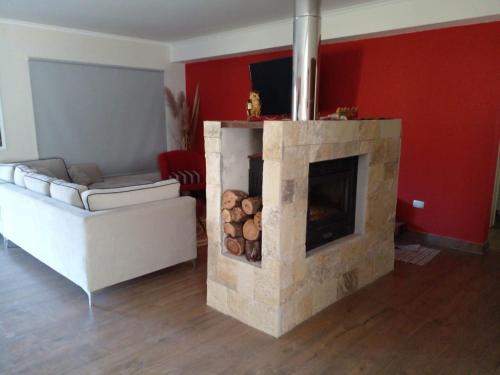 sala de estar con chimenea de piedra y sofá en La Fermina en Villa Giardino