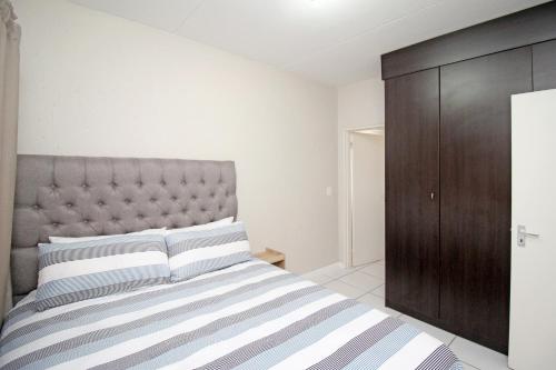a bedroom with a large bed and a brown cabinet at GREENWICH 2 bedroom 2 bath serv apart with 24hrs electricity in Sandton