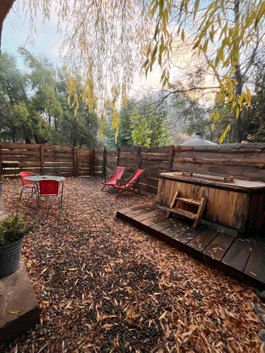 a backyard with chairs and a table and a fence at El Encanto del Manzano & Espacio Vittalia Spa in San José de Maipo