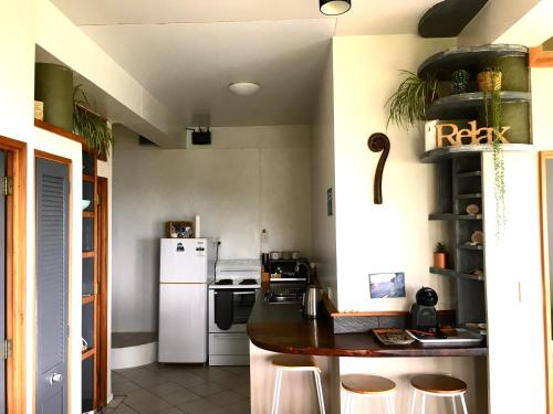 a kitchen with a white refrigerator and a counter with stools at 90 Mile Paradise Ahipara in Ahipara
