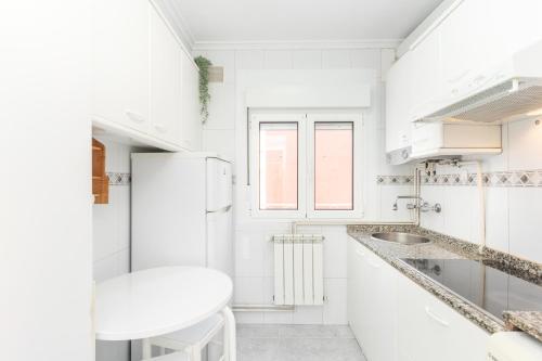 a white kitchen with a sink and a refrigerator at De la cama a la mar in Luanco