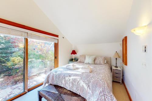 a bedroom with a bed and a large window at Little Brown House in Glen Arbor