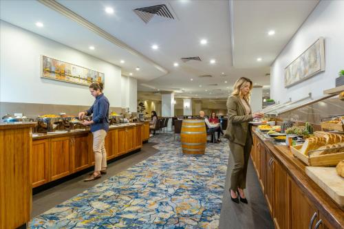 two people standing at the buffet in a hotel at Hotel Grand Chancellor Adelaide in Adelaide