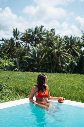 a woman in a bikini sitting in a swimming pool at Woywoy Escape Samu (Adults Only) in Ubud