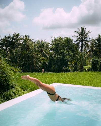 a woman in a swimming pool with her leg in the air at Woywoy Escape Samu (Adults Only) in Ubud