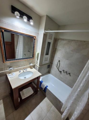 a bathroom with a tub and a sink and a mirror at Hotel Pórtico Norte in Tartagal
