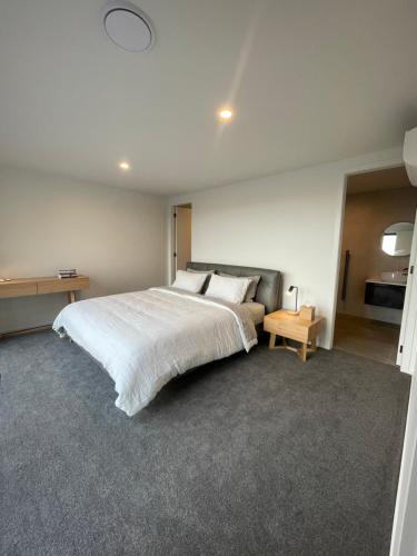 a bedroom with a large white bed and a table at Luxury at the Lake in Hamilton
