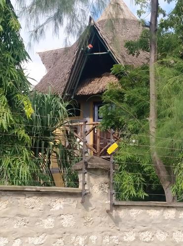 a house with a thatched roof and a porch at Kikambala Eco Villas in Mombasa