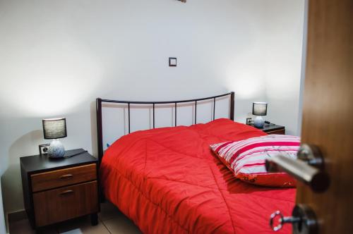 a bedroom with a red bed with two night stands and two lamps at g.home in Tríkala