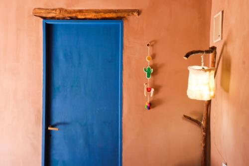 a blue door on a wall next to a lamp at El Cerrito in Maimará