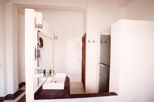 a white bathroom with a sink and a shower at The Columns in Kampot