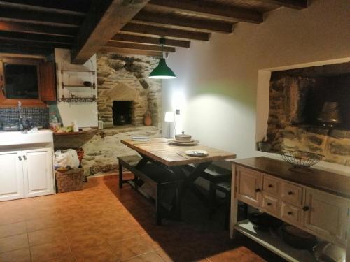a kitchen with a table and a stone fireplace at Casa de piedra en pequeña aldea de Ortigueira 