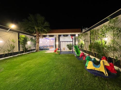 una casa con un patio verde con juguetes en la hierba en شاليه فاملي دي family day, en Hail