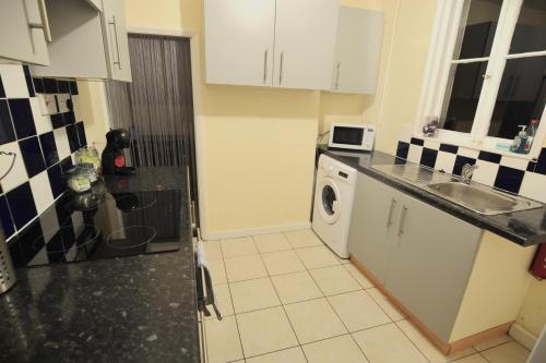 a kitchen with a sink and a washing machine at Rose House Entire House WiFi 3 Bed Garden Maidstone - Kent in Maidstone