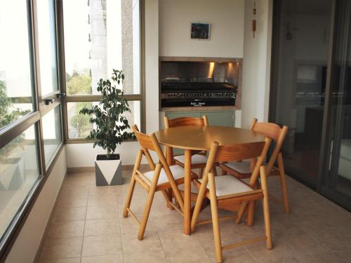 una mesa de madera y sillas en una cocina con ventana en Departamento PREMIUM Zona Golf, piso exclusivo con vista plena al mar en Mar del Plata