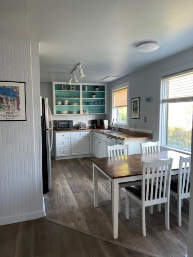 a kitchen with a wooden table and white cabinets at Guesthouse Cannon Beach in Cannon Beach