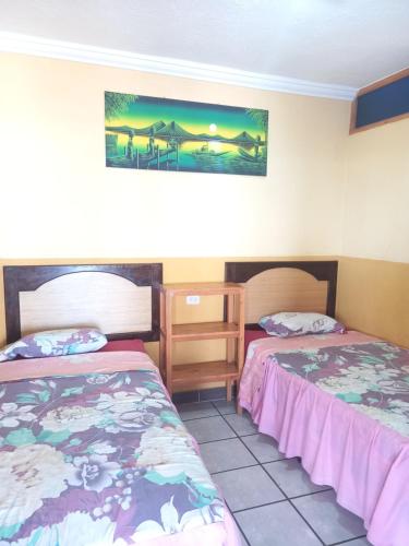 a room with two beds and a dresser at HOTEL PENELEU in San Pedro La Laguna