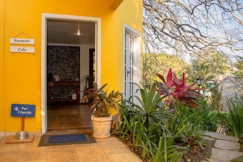 Una casa amarilla con plantas delante. en Villa Bella Ferradura, en Búzios