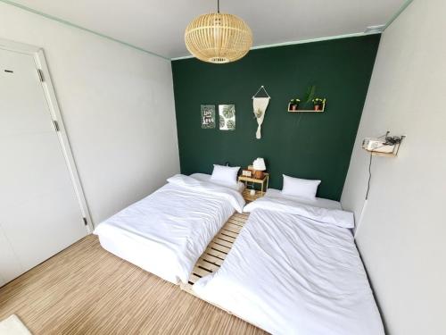 2 Betten in einem Zimmer mit grüner Wand in der Unterkunft Eeumgil in Daegu