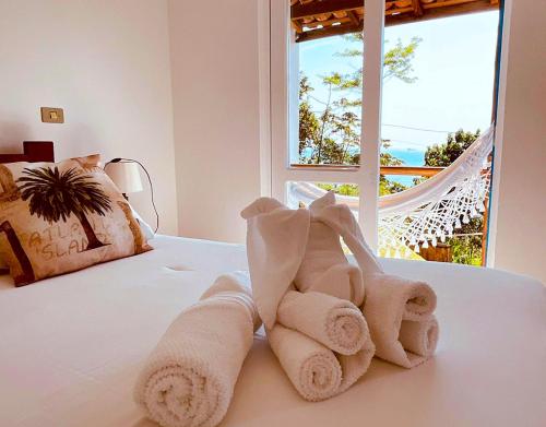 a pile of towels sitting on a bed with a window at VELINN Pousada 8 Ilhas in Ilhabela