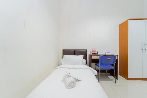a bedroom with a bed and a desk and a blue chair at Apik Kamila BSD in Tjilandak