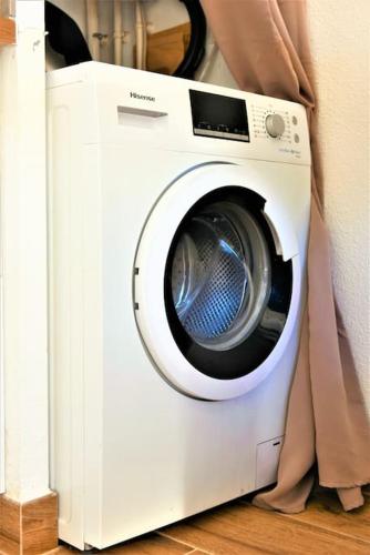 a white washing machine sitting next to a curtain at EMbnb - Studio Near Geneva - S204,4 in Étrembières