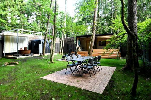 un tavolo e sedie in un cortile con una casa di Fuji Fumoto Forest Hotspring ふもとの森温泉 a Fujikawaguchiko