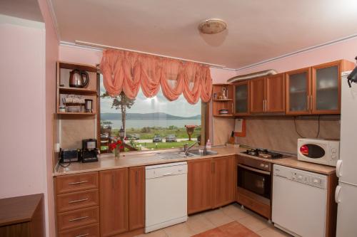a kitchen with wooden cabinets and a large window at Guest house Lidia in Tsigov Chark