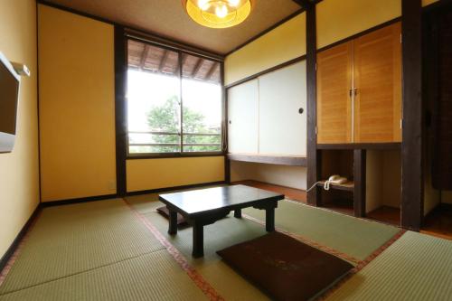 a living room with a table and a window at Tabinoyado Asonoyu in Aso