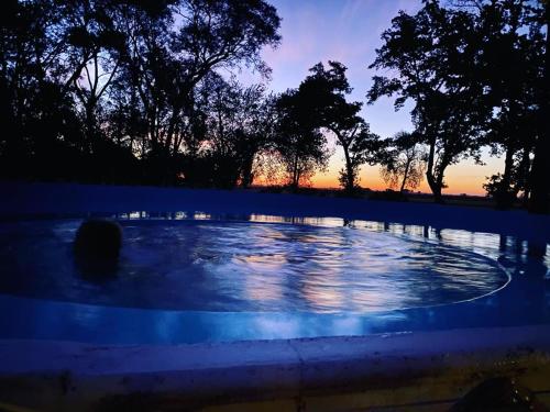 una piscina de agua con una puesta de sol en el fondo en Estancia Santa Margarita 1873 en Junín