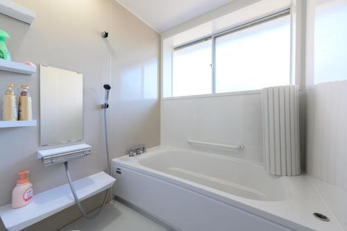 宇和島市にあるすなだの家の白いバスルーム(バスタブ付)、窓が備わります。