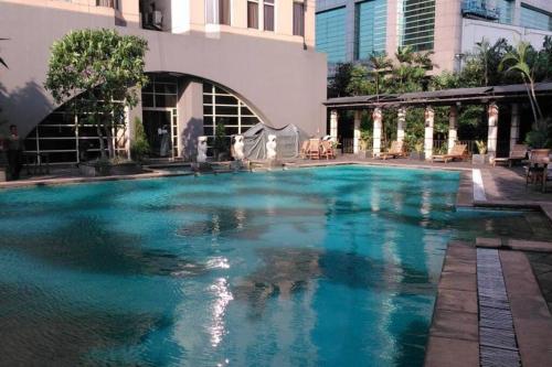 a swimming pool with blue water in a building at Slipi Apartment 2BR in Jakarta