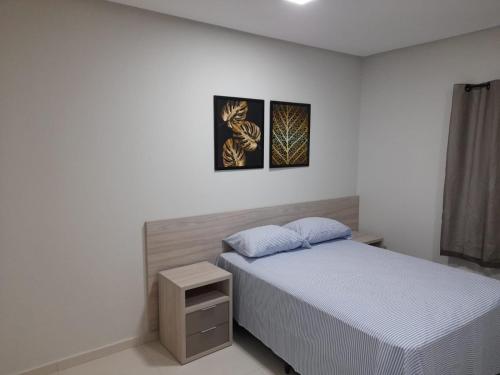 a bedroom with a bed and two pictures on the wall at FLATS TAVARES ARAUJO 202 in Garanhuns